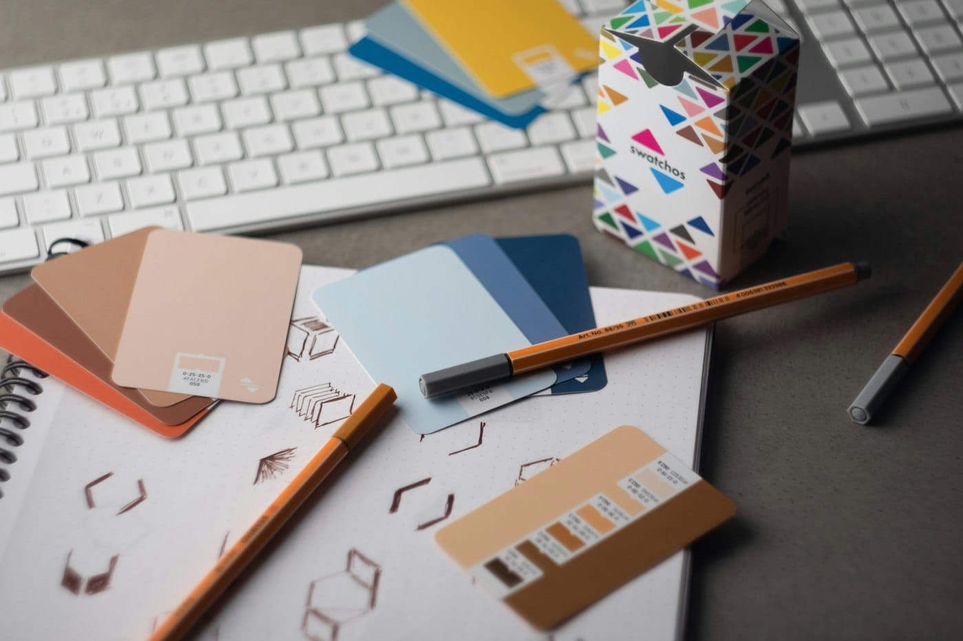 Colour swatch cards, pencils and packaging sketches on a designer's desk
