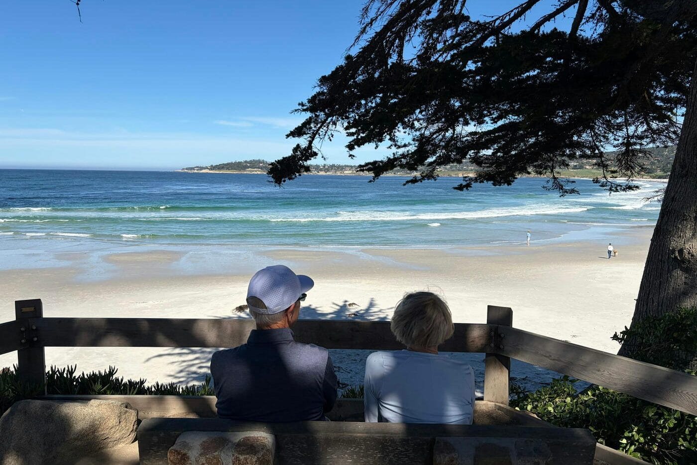 Couple sitting on a bench overlooking a quiet beach