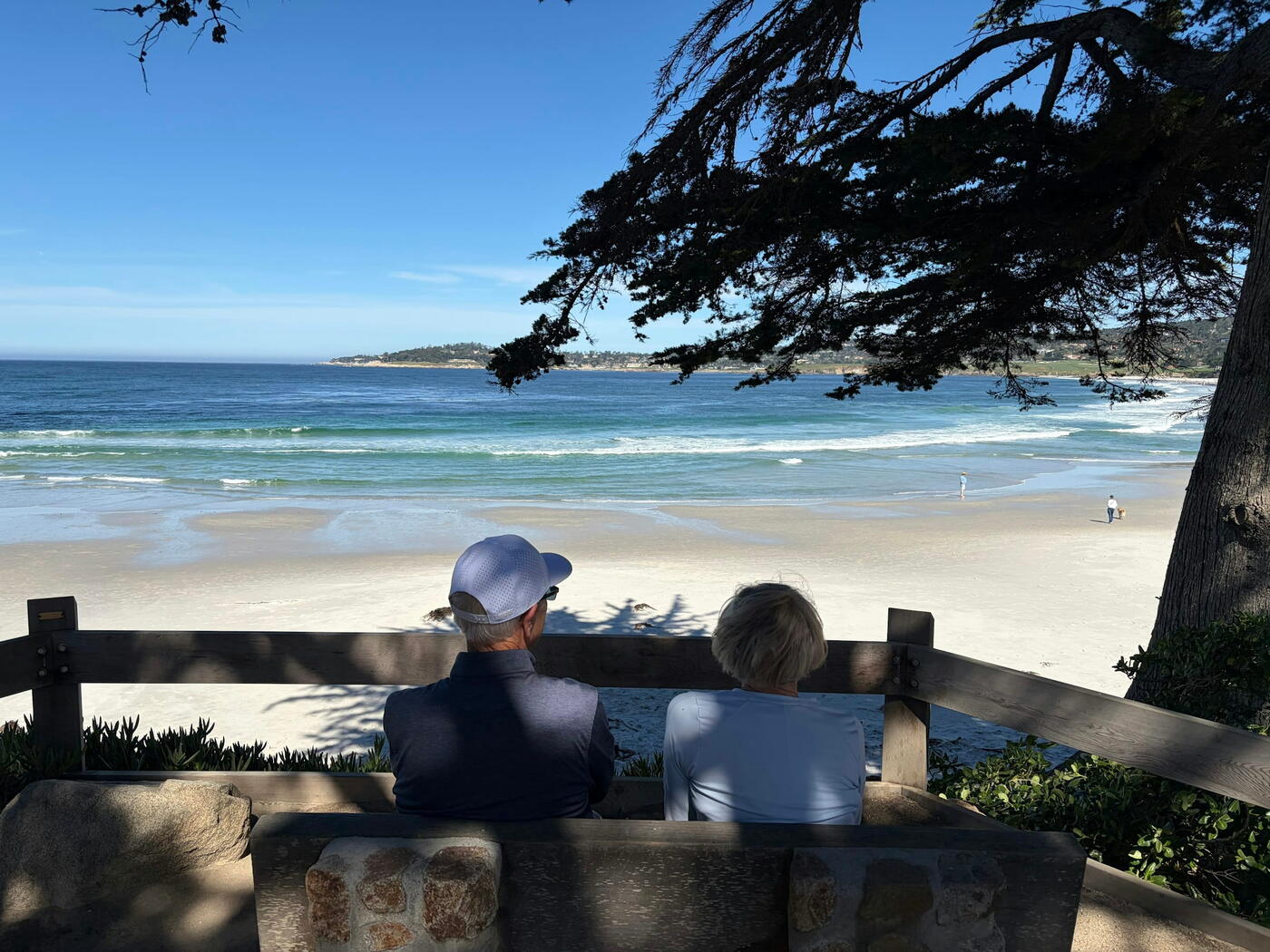 Couple sitting on a bench overlooking a quiet beach