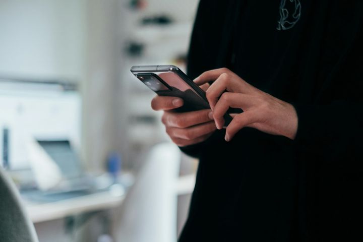 Hands scrolling smartphone Hands scrolling on a smartphone against dark clothing