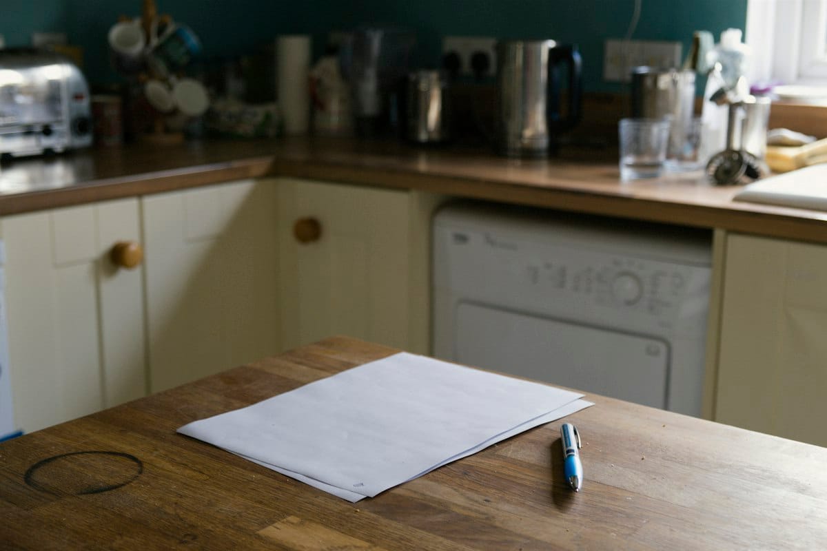 Sheets of paper and a pen on a timber kitchen bench