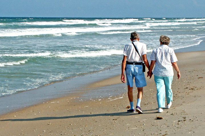 Older couple walking hand in hand along the shoreline