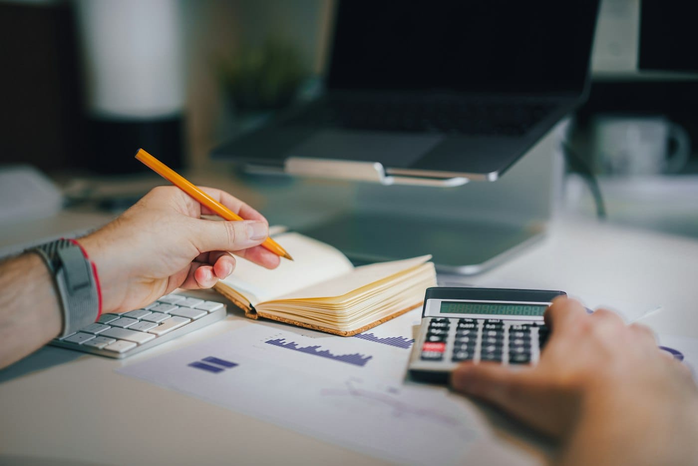 Business owner working through figures with a notebook, calculator and laptop