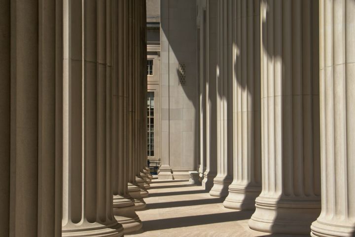 Row of stone columns casting shadows along a portico