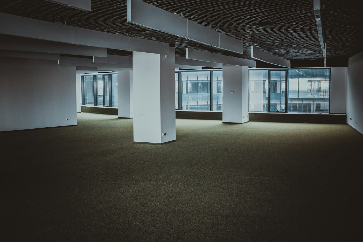 Vacant office floor with bare carpet and city windows